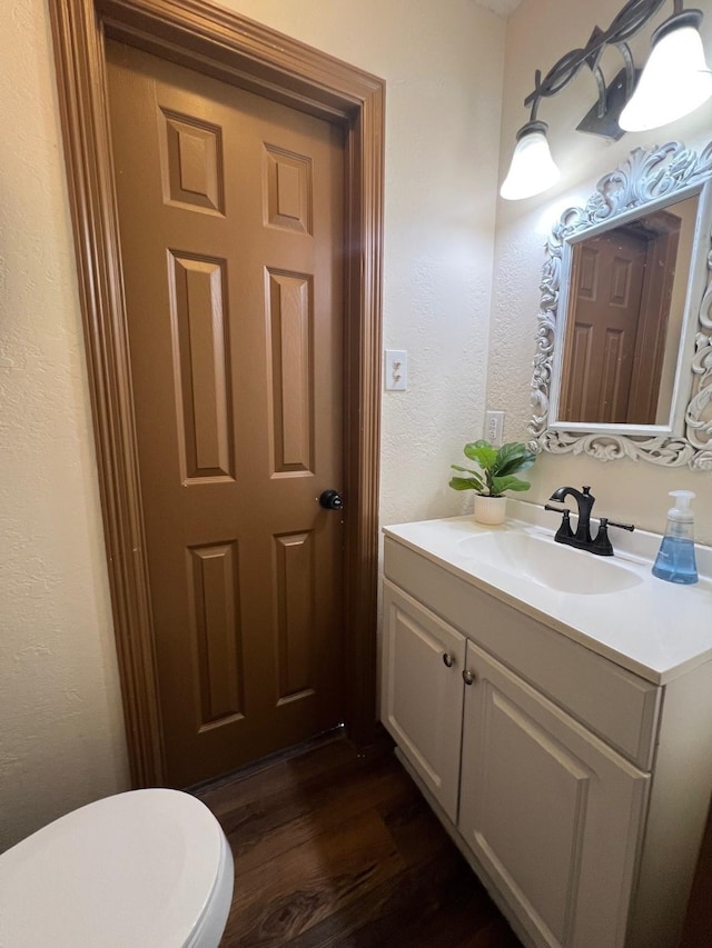 bathroom with vanity, toilet, and wood finished floors
