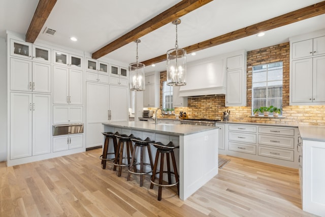 6622 Blue Valley Ln, Dallas, TX 75214 - kitchen with premium range hood, light wood finished floors, visible vents, and a wealth of natural light