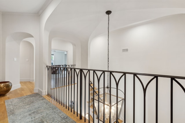 6622 Blue Valley Ln, Dallas, TX 75214 - hallway featuring baseboards, an upstairs landing, visible vents, arched walkways, and wood finished floors