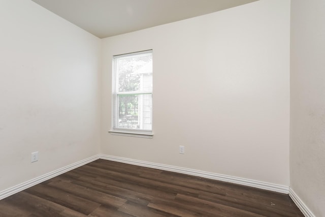 spare room with dark wood-style flooring and baseboards