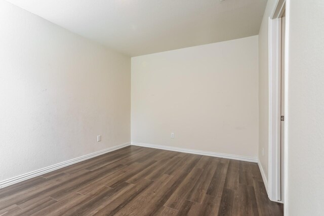 spare room with dark wood-style floors and baseboards