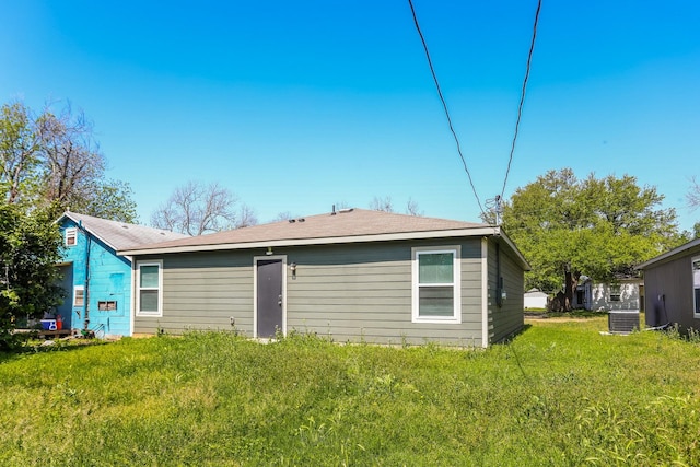 rear view of house with cooling unit and a lawn