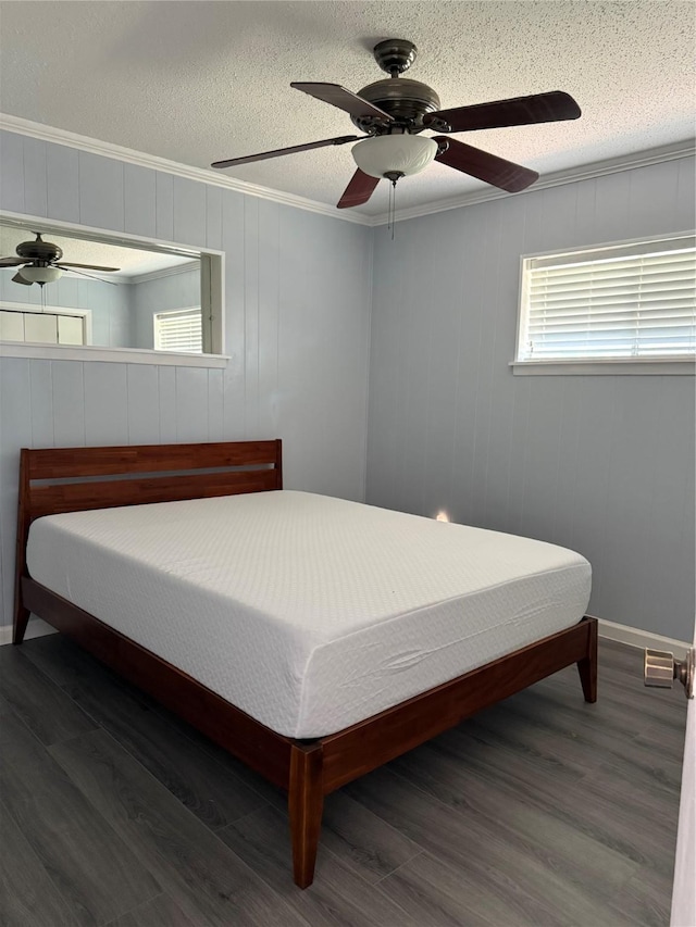 bedroom with a textured ceiling, baseboards, ornamental molding, wood finished floors, and a ceiling fan