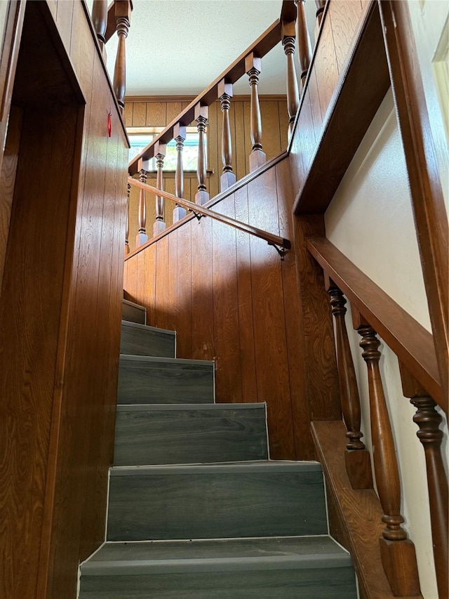 stairway featuring wood walls