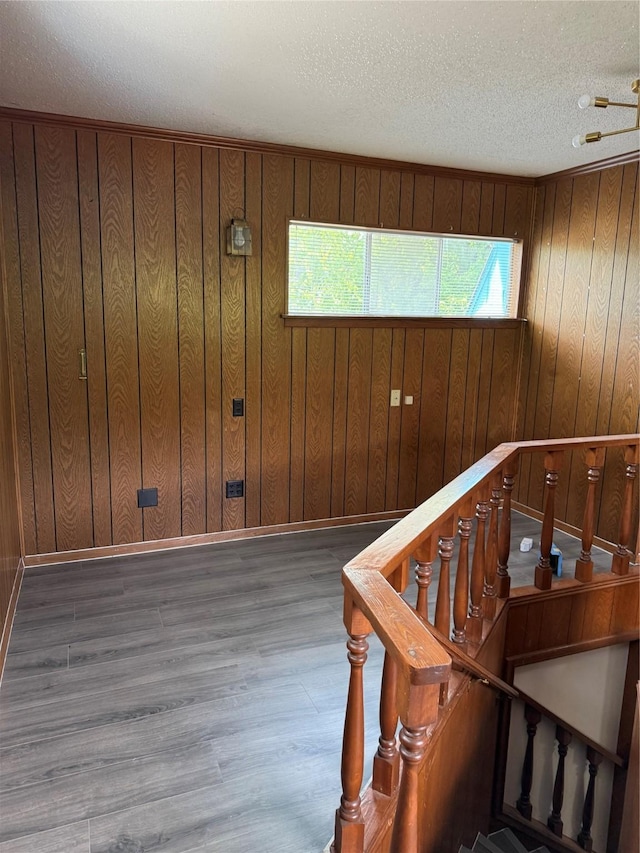 stairway with a textured ceiling, wood walls, wood finished floors, and baseboards