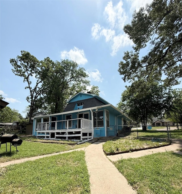 farmhouse-style home with a front yard, covered porch, and fence