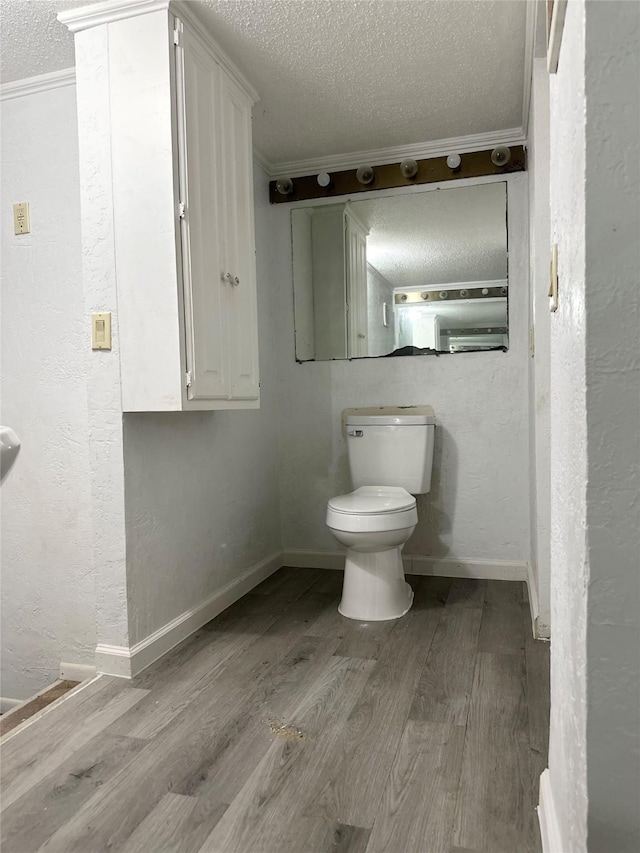 bathroom with baseboards, wood finished floors, a textured ceiling, and toilet
