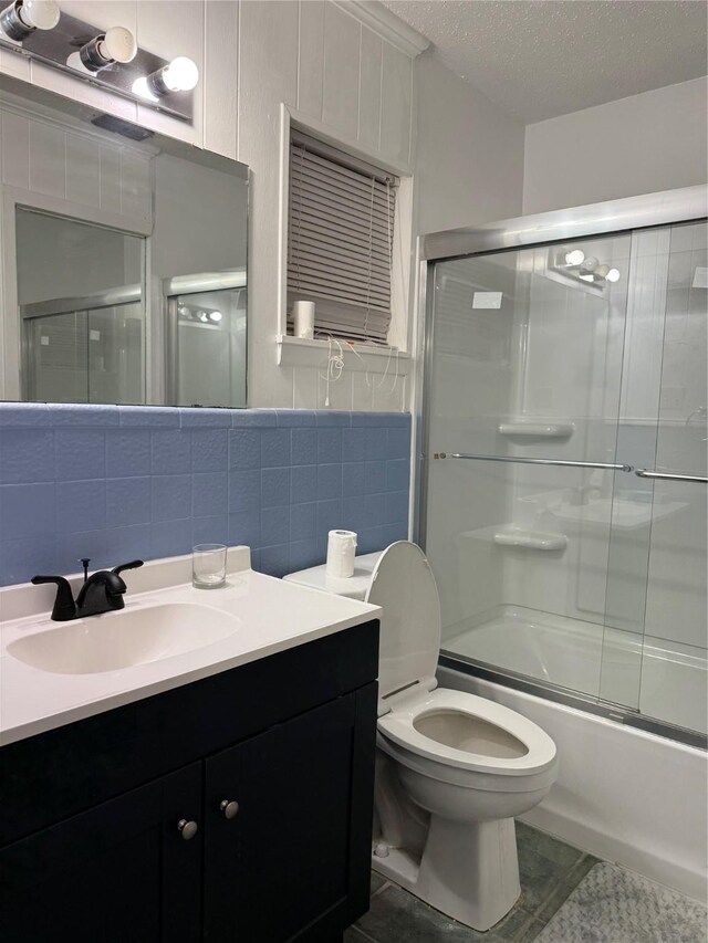 full bathroom featuring a textured ceiling, enclosed tub / shower combo, toilet, vanity, and tile patterned flooring