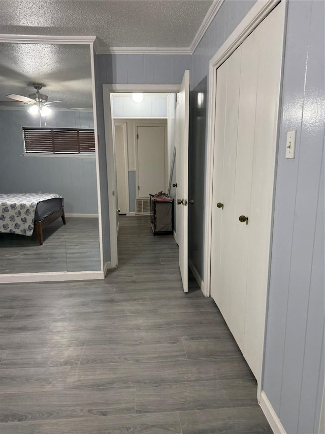 interior space with crown molding, a textured ceiling, wood finished floors, and baseboards