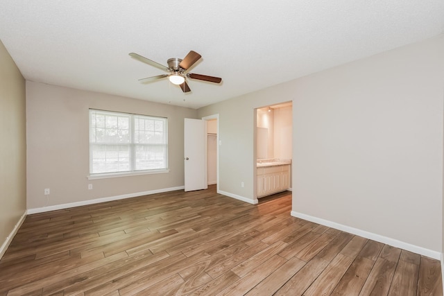 spare room featuring ceiling fan, light wood-style floors, and baseboards