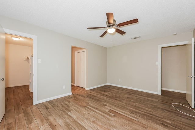 empty room with visible vents, baseboards, a ceiling fan, and wood finished floors