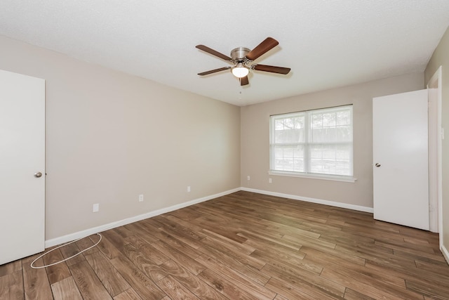 empty room featuring baseboards, wood finished floors, and ceiling fan