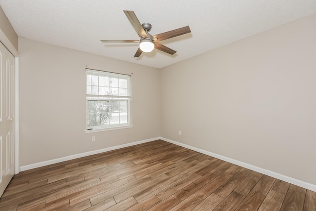 spare room featuring ceiling fan, baseboards, and wood finished floors