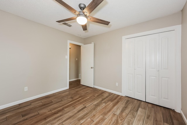 unfurnished bedroom with visible vents, baseboards, a closet, and wood finished floors