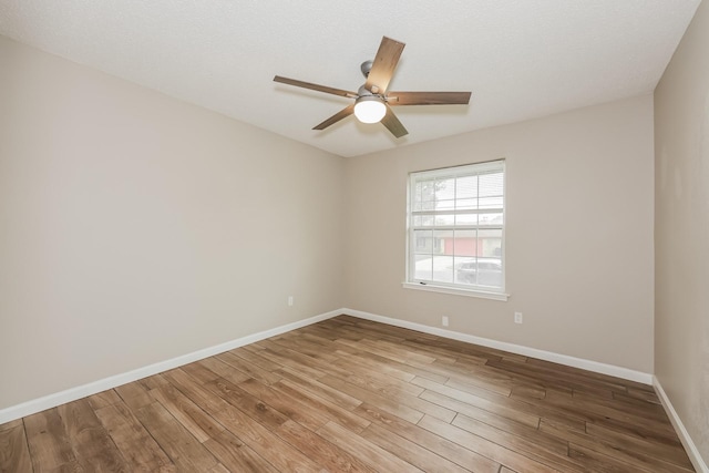 empty room with wood finished floors, baseboards, and a ceiling fan