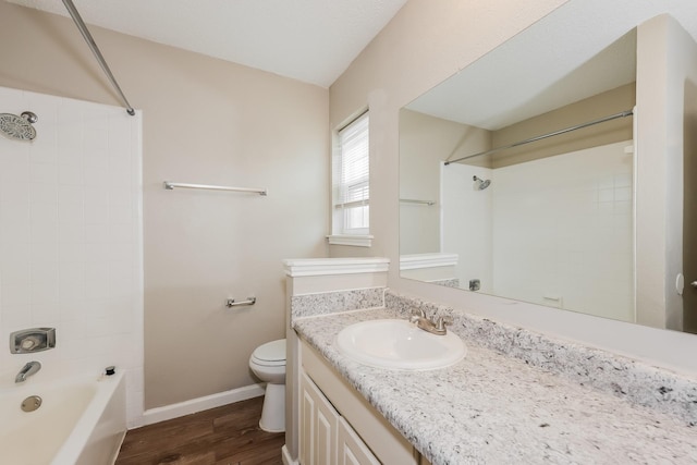 bathroom featuring vanity, shower / tub combination, toilet, wood finished floors, and baseboards