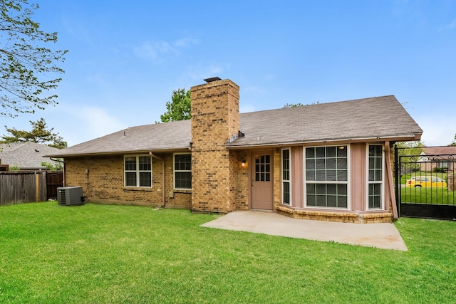back of house featuring central AC unit, a lawn, a chimney, fence, and brick siding