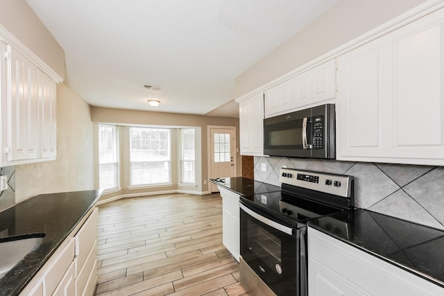 kitchen with stainless steel appliances, white cabinets, backsplash, and dark countertops
