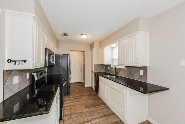 kitchen with light wood-style floors, white cabinets, visible vents, a sink, and stainless steel appliances