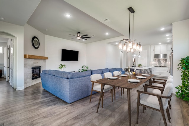 3128 Lexington Dr, Celina, TX 75009 - dining space featuring wood finished floors, ceiling fan, recessed lighting, a glass covered fireplace, and arched walkways