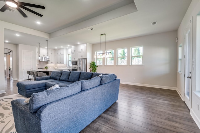 3128 Lexington Dr, Celina, TX 75009 - living room featuring a raised ceiling, a ceiling fan, a chandelier, dark wood-style floors, and recessed lighting