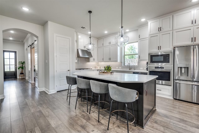 3128 Lexington Dr, Celina, TX 75009 - kitchen with stainless steel appliances, under cabinet range hood, a center island, arched walkways, and a breakfast bar