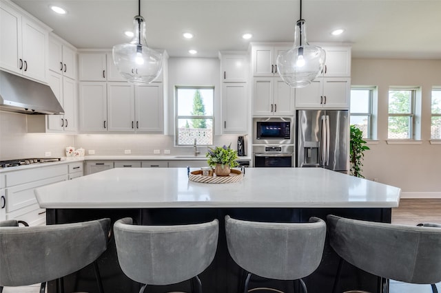 3128 Lexington Dr, Celina, TX 75009 - kitchen with stainless steel appliances, under cabinet range hood, plenty of natural light, a breakfast bar, and recessed lighting