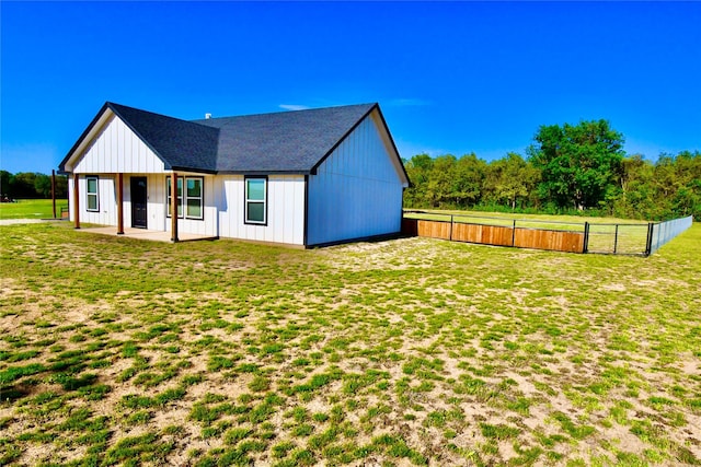 rear view of property with a yard, fence, a patio, and a shingled roof