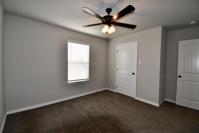 unfurnished room with ceiling fan, dark colored carpet, and baseboards