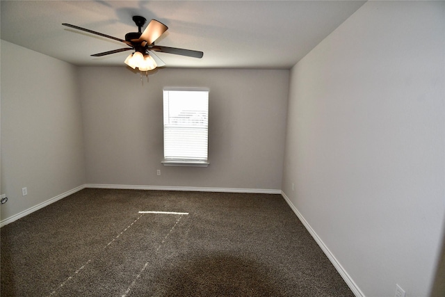 empty room with dark carpet, ceiling fan, and baseboards