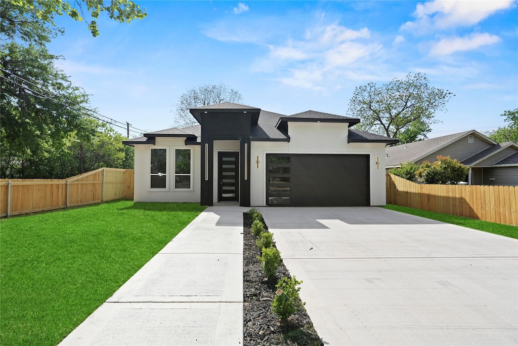 view of front of house with stucco siding, driveway, a front lawn, a garage, and fence