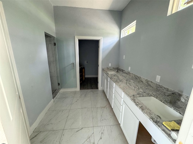 409 S Main St, Bonham, TX 75418 - bathroom featuring marble look tiles, a stall shower, double vanity, and baseboards