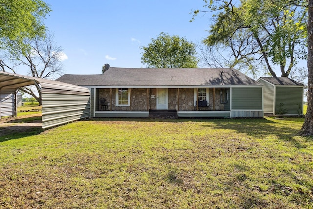 view of front of house with a front yard, a detached carport, and a shingled roof