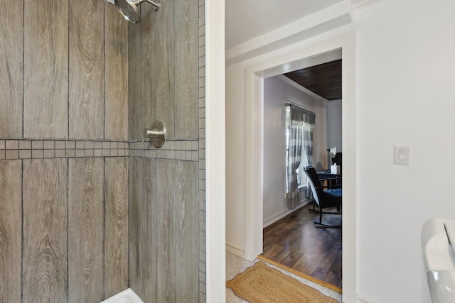 interior space featuring tiled shower, baseboards, and wood finished floors