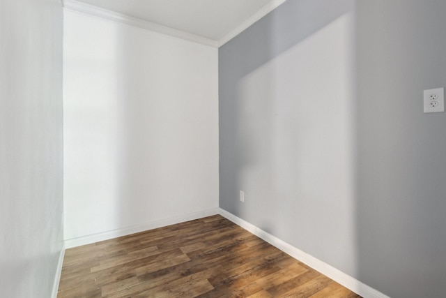 empty room with dark wood-style floors, baseboards, and crown molding