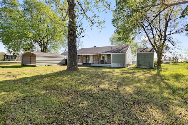 rear view of property with a carport, a yard, an outbuilding, and a storage unit