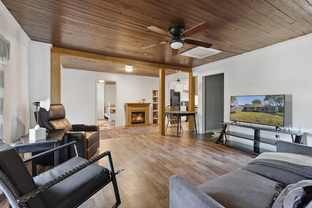 living area with a glass covered fireplace, wooden ceiling, a ceiling fan, and wood finished floors