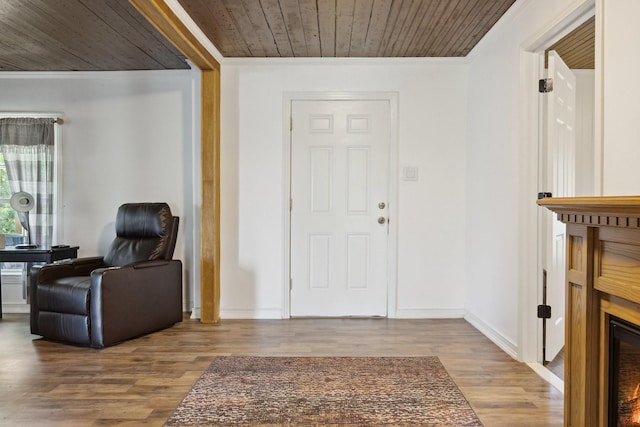 foyer with wood ceiling, wood finished floors, crown molding, and baseboards