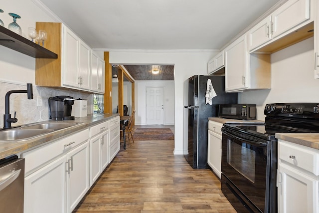 kitchen featuring open shelves, white cabinets, black appliances, wood finished floors, and a sink