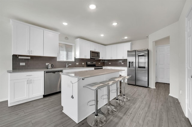 1335 Panorama Dr, Forney, TX 75126 - kitchen with a center island, a sink, appliances with stainless steel finishes, a kitchen bar, and white cabinetry