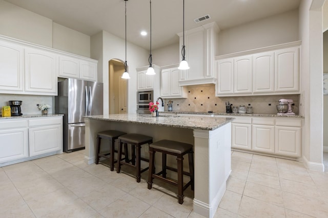 kitchen featuring light tile patterned floors, visible vents, a sink, stainless steel appliances, and decorative backsplash