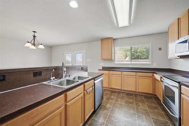 kitchen featuring dark countertops, a notable chandelier, a sink, stainless steel appliances, and pendant lighting