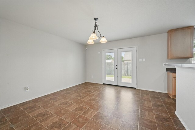 unfurnished dining area featuring french doors, baseboards, and a chandelier