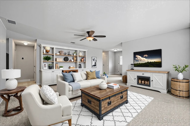 living room featuring ceiling fan, light carpet, a fireplace, baseboards, and visible vents