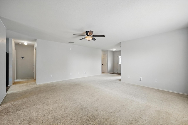 spare room featuring a ceiling fan, baseboards, visible vents, and light carpet