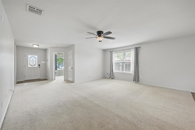 unfurnished living room with a healthy amount of sunlight, light carpet, a ceiling fan, and visible vents