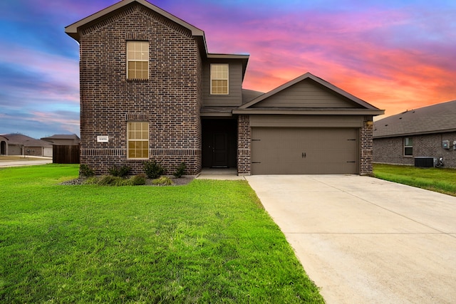 traditional-style home with central AC unit, a yard, concrete driveway, brick siding, and a garage
