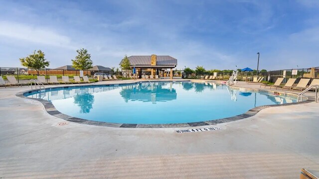 pool with a patio area and fence