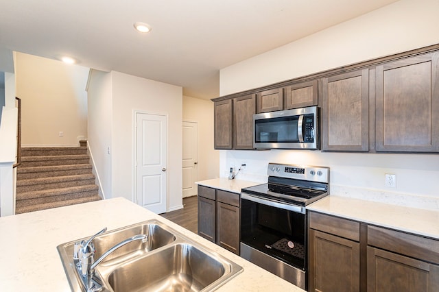 kitchen with dark brown cabinetry, a sink, recessed lighting, and appliances with stainless steel finishes