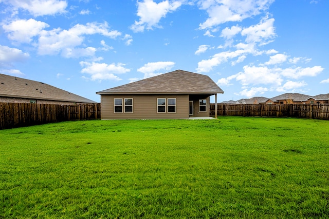 back of property with a fenced backyard and a yard
